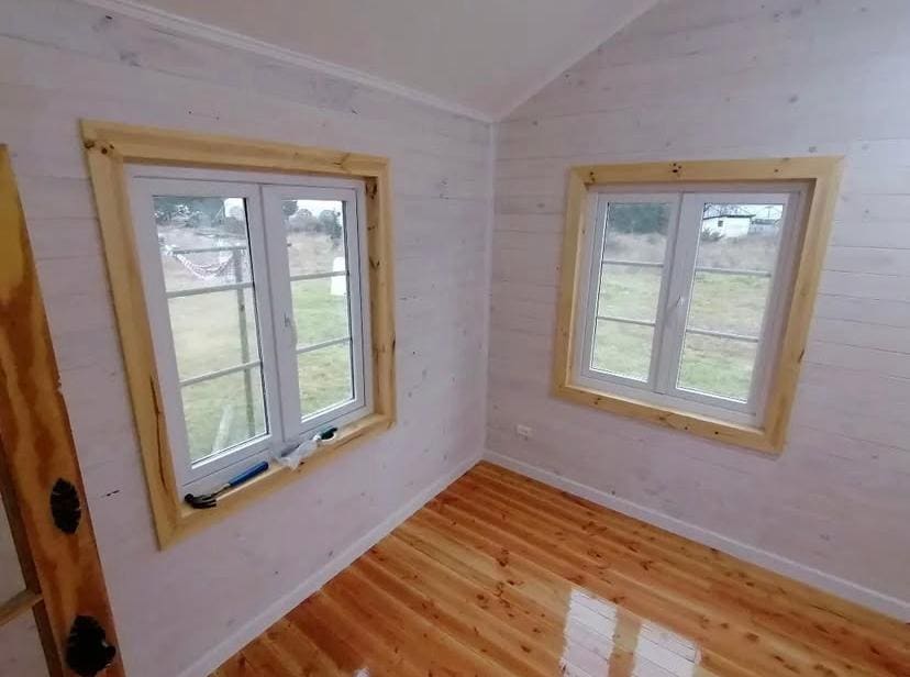 Interior recién terminado con piso de pino barnizado brillante y ventanas con marcos de madera
