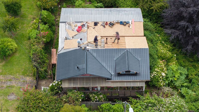Vista aérea del equipo instalando placas de OSB y estructura de techumbre nueva sobre una casa